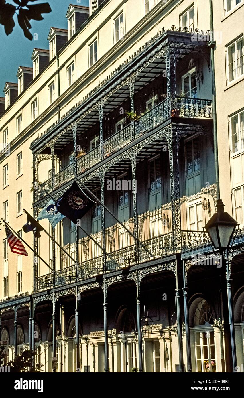 Balconies and overhangs of lacy black wrought iron enhance the 6-story facade of the Omni Royal Orleans, one of the most historic hotels in the famed French Quarter of New Orleans, Louisiana, USA. Such ornamental ironworks are hallmarks of the city's varied architecture, including the Renaissance Revival style shown here. Additional guestroom balconies of wrought iron have been added since this photograph was taken in 1984. Once known as the St. Louis, the current hotel was built in 1960 to replace earlier grand lodgings dating as far back as 1843 that were destroyed by fire and a hurricane. Stock Photo