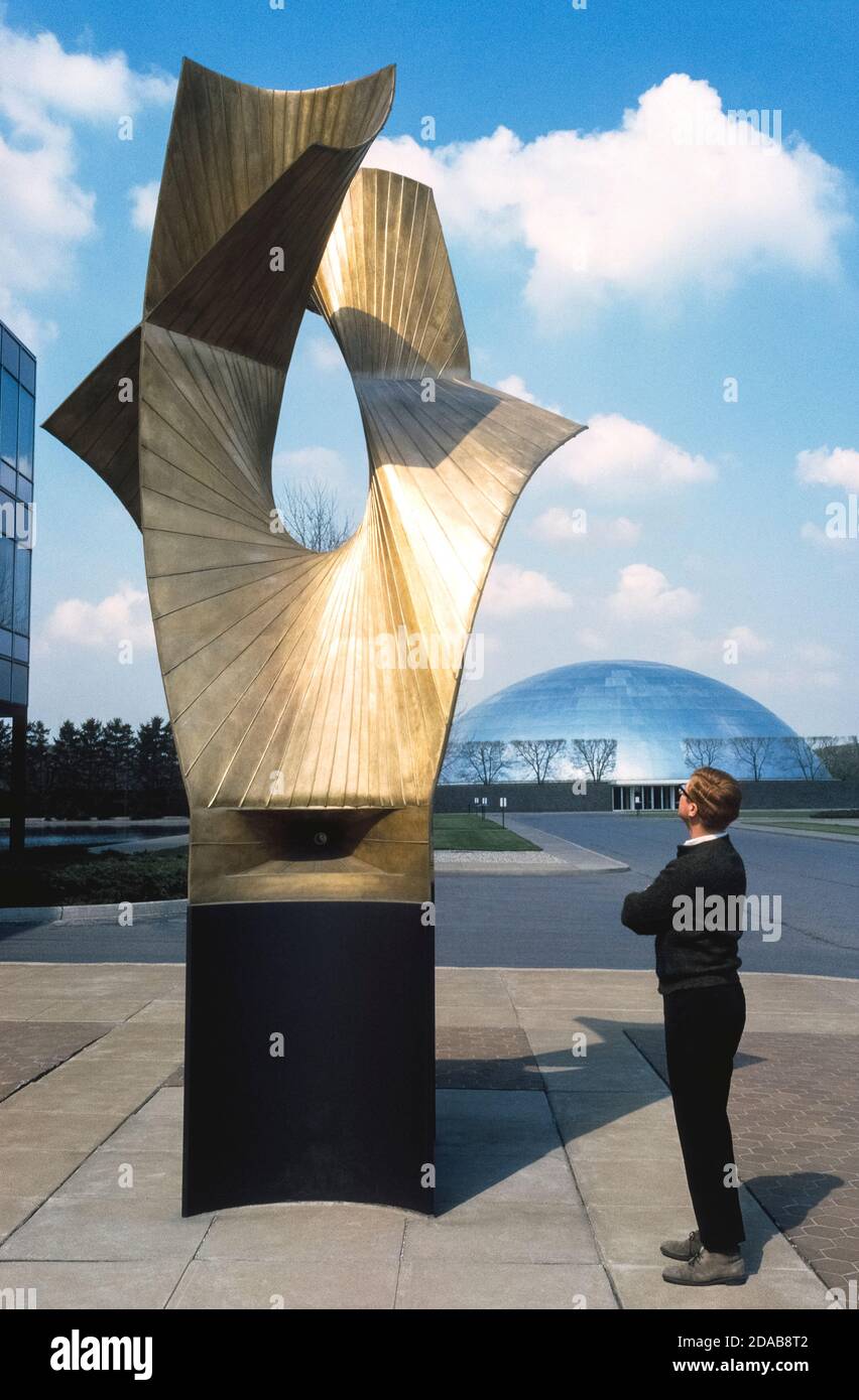 A visitor admires the towering outdoor artwork of famed sculptor Alexander Calder at the General Motors Technical Center in the Detroit suburb of Warren, Michigan, USA. Designed by internationally-renowned father and son architects, Eliel and Eero Saarinen, the modernistic GM Tech Center represented industrial America when it opened in 1956 with 25 buildings spread over a 320-acres (130 hectares). The widely-praised complex ushered in a new and novel architectural theme: the corporate campus, which hailed the arrival of corporations as centers of learning, scientific patronage, and power. Stock Photo