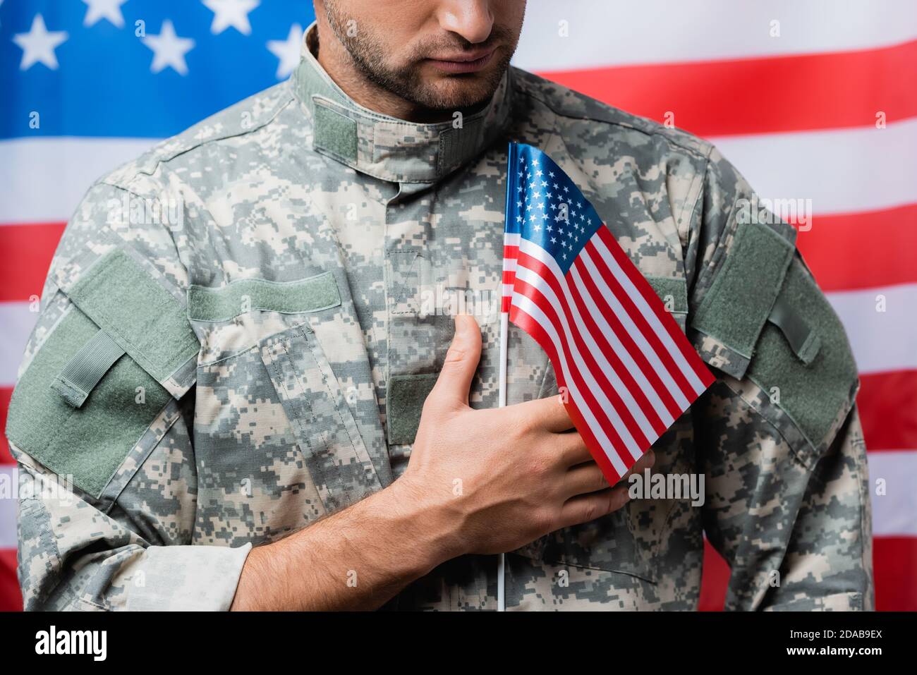 cropped view of patriotic military man in uniform holding small american  flag on blurred background Stock Photo - Alamy