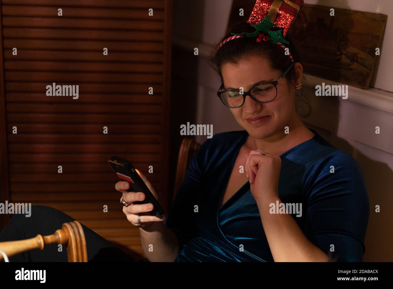 Young woman with christmas hair decor looking not amused into her mobile phone at christmas. Stock Photo