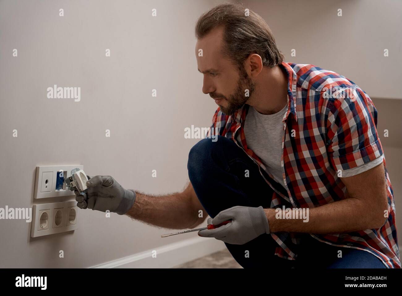 Young caucasian electrical engineer installing power sockets Stock Photo
