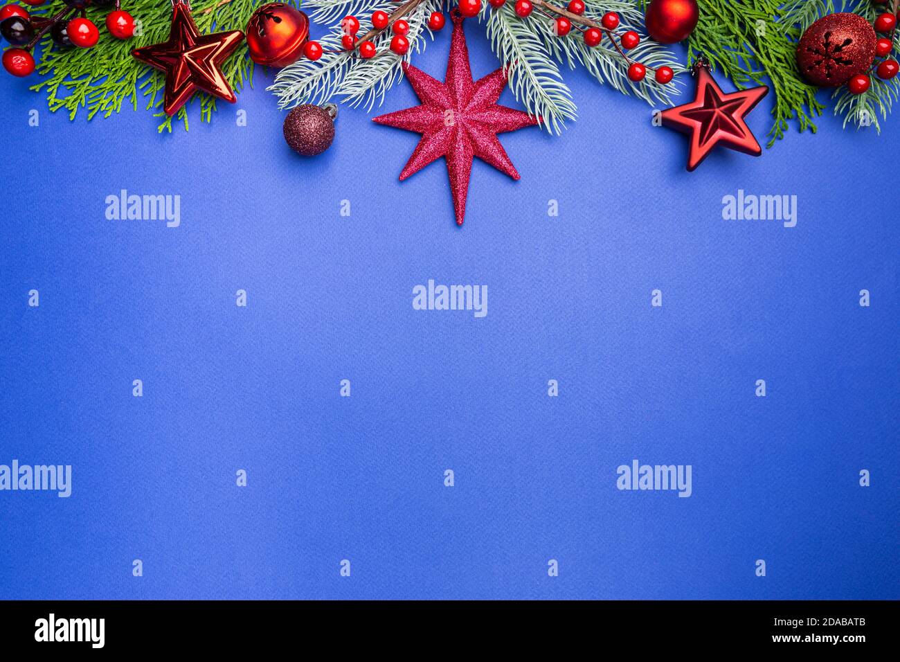 Christmas holidays composition with christmas decorations, red berries and thuja branches on blue background with copy space, top view Stock Photo