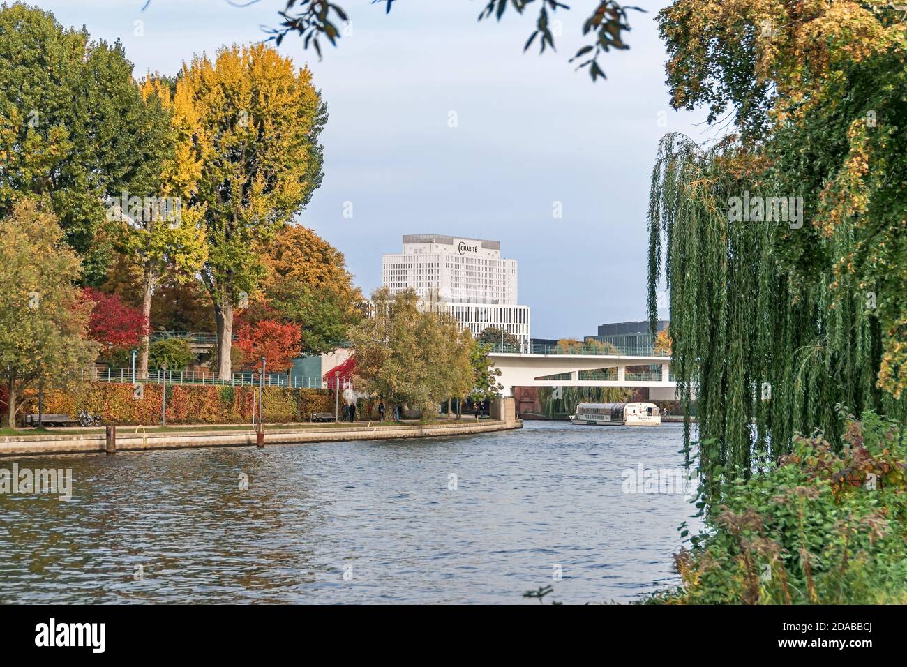 Berlin, Germany - October 20, 2020: Banks of the river Spree lined with autumn coloured trees and tourist boat, the building of the Charite, Europe's Stock Photo