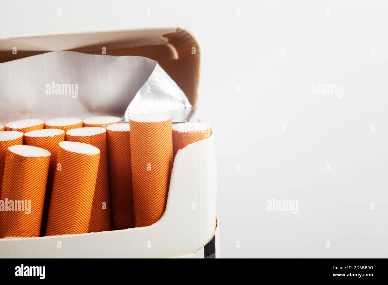 Open pack of cigarettes with a red filter close-up on a white background, place for your text. Stock Photo