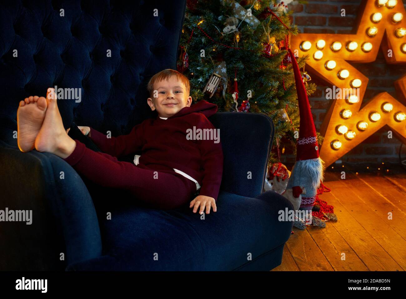 A cheerful and happy boy is lying in a chair. Child waiting for Christmas holidays and gifts Stock Photo