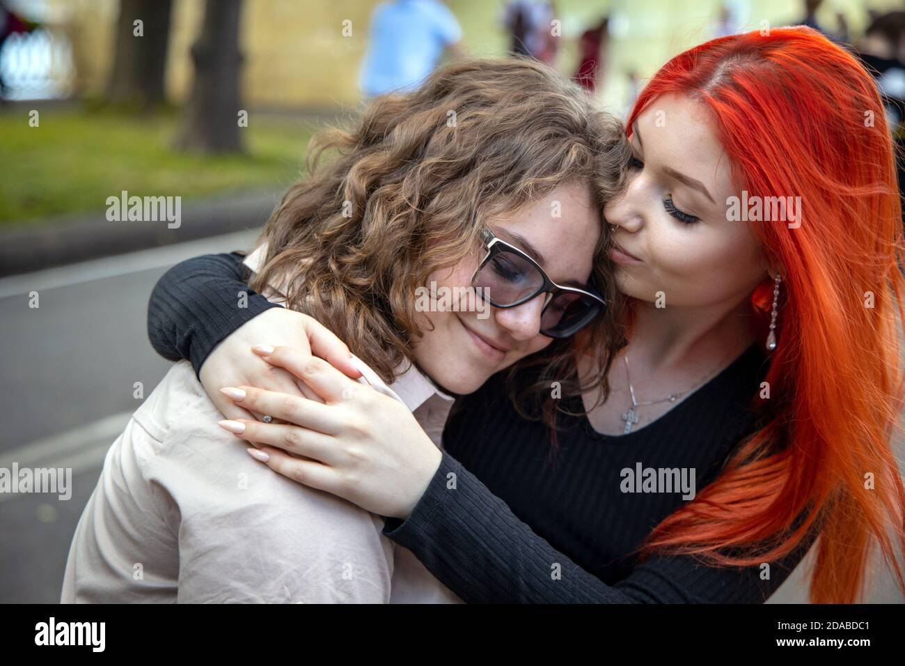 Russia. Moscow 10 July 2020: Two friends a redhead and a brunette meet on a city street and hug Stock Photo