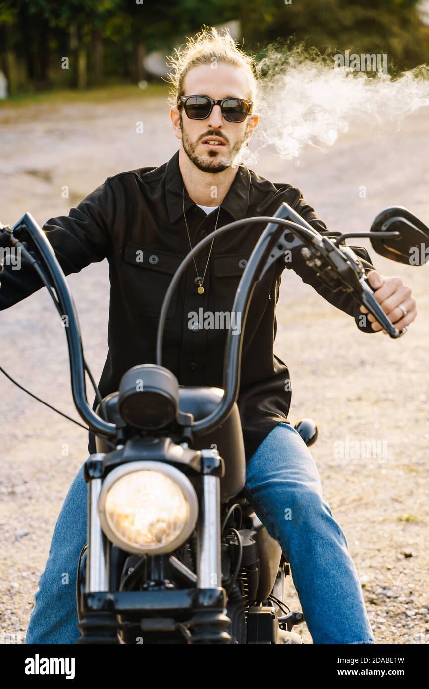 Smoking Riders Vertical photo of a young man with sunglasses smoking while riding a ...