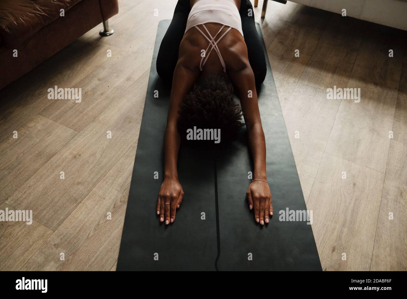 Mixed race woman practising yoga and breathing techniques stretching at home, fitness concept, top down shot Stock Photo