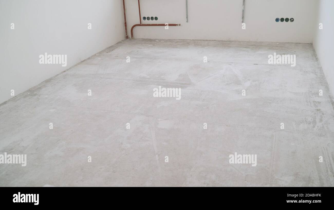 Concrete floor in a new apartment. Concrete floor before processing. Unfinished building interior, detail of a white room. empty home renovation Stock Photo