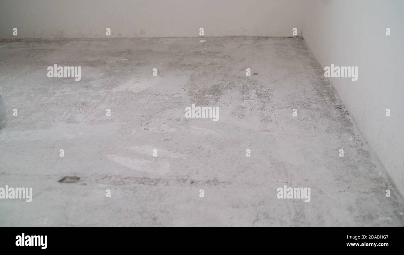 Concrete floor in a new apartment. Concrete floor before processing. Unfinished building interior, detail of a white room. empty home renovation Stock Photo