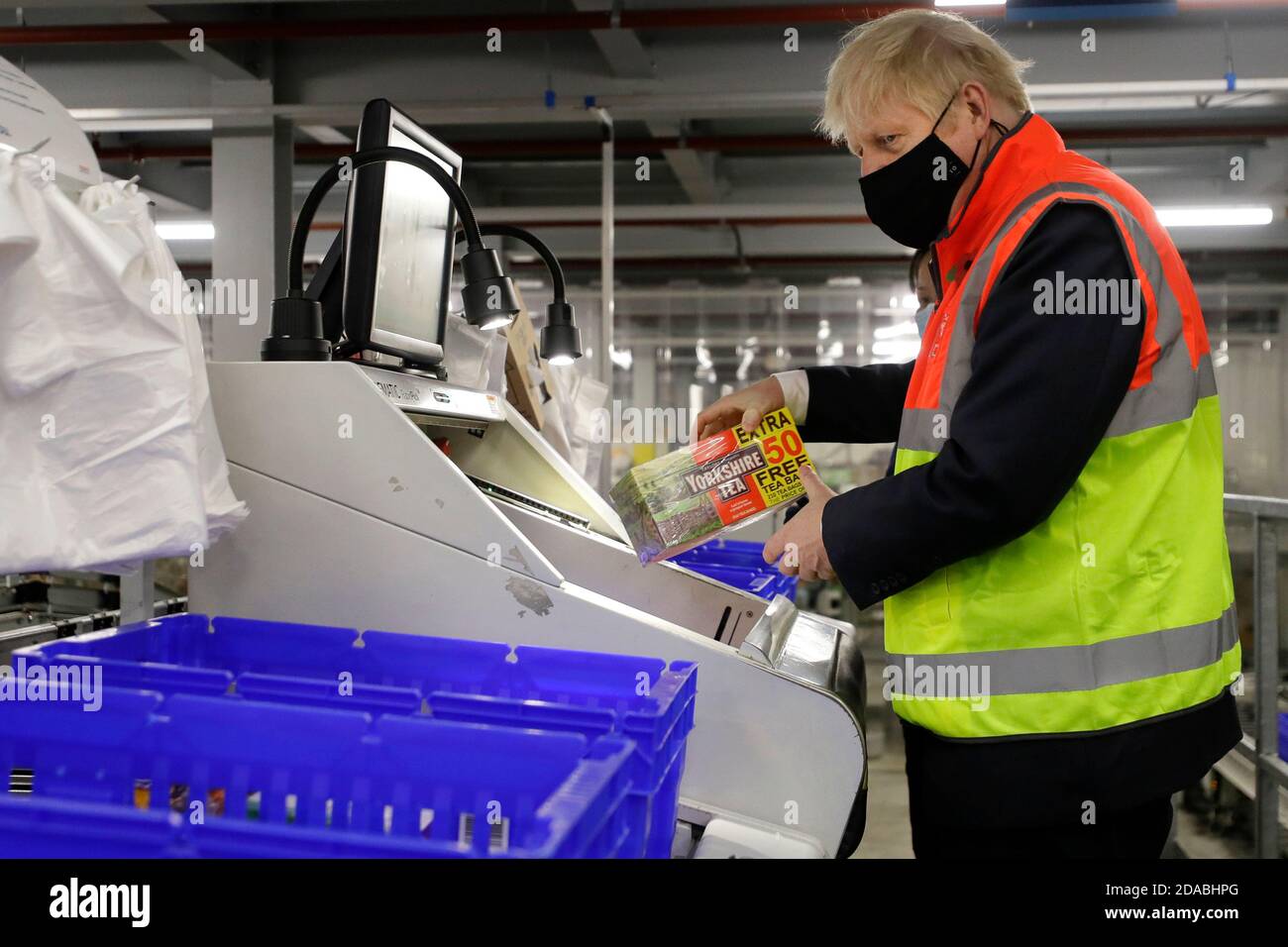 Prime Minister Boris Johnson loads produce into baskets during a visit to the Tesco Erith