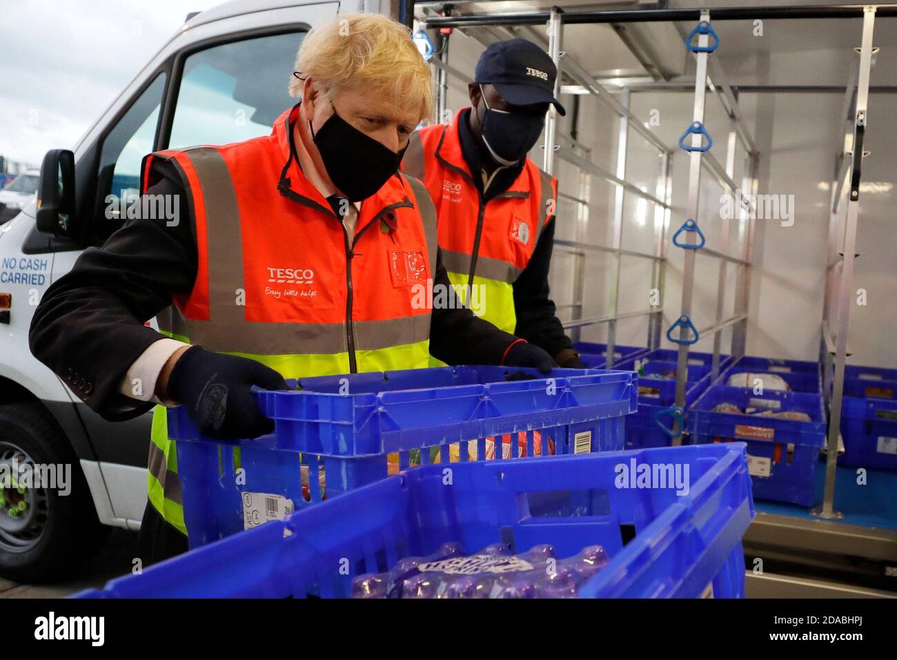 Prime Minister Boris Johnson loads a delivery van with a basket of