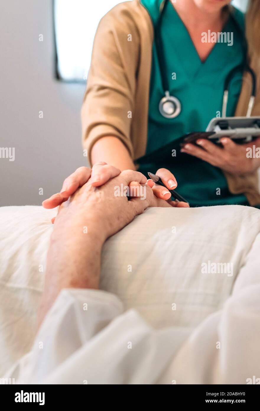 Female doctor comforting older patient Stock Photo