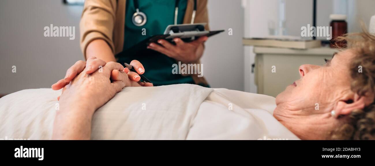 Female doctor comforting older patient Stock Photo