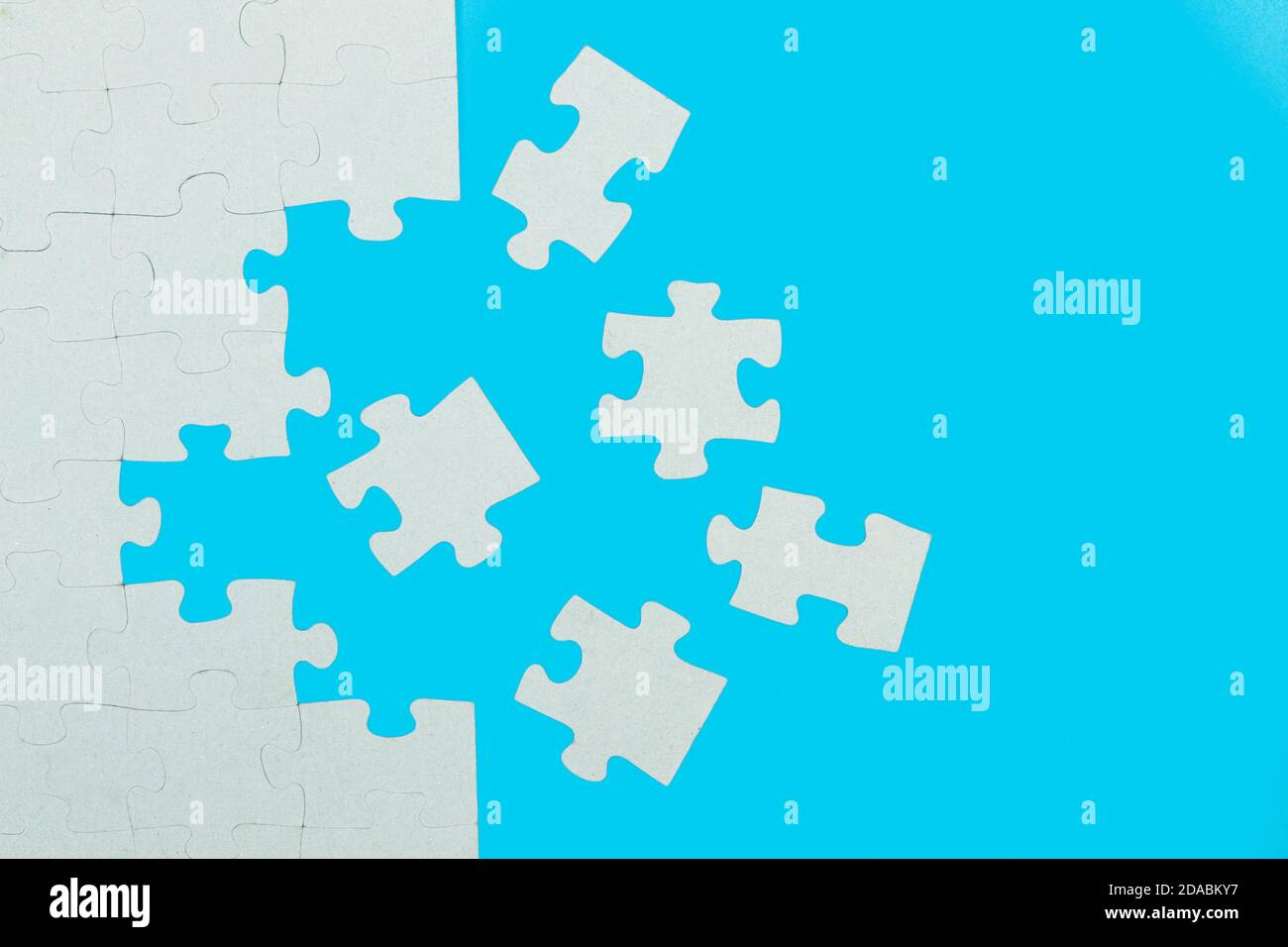 A unfinished puzzle with pieces on a light blue background Stock Photo
