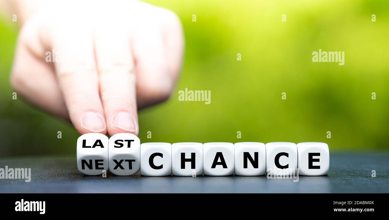 Hand turns dice and changes the expression 'next chance' to 'last chance'. Stock Photo