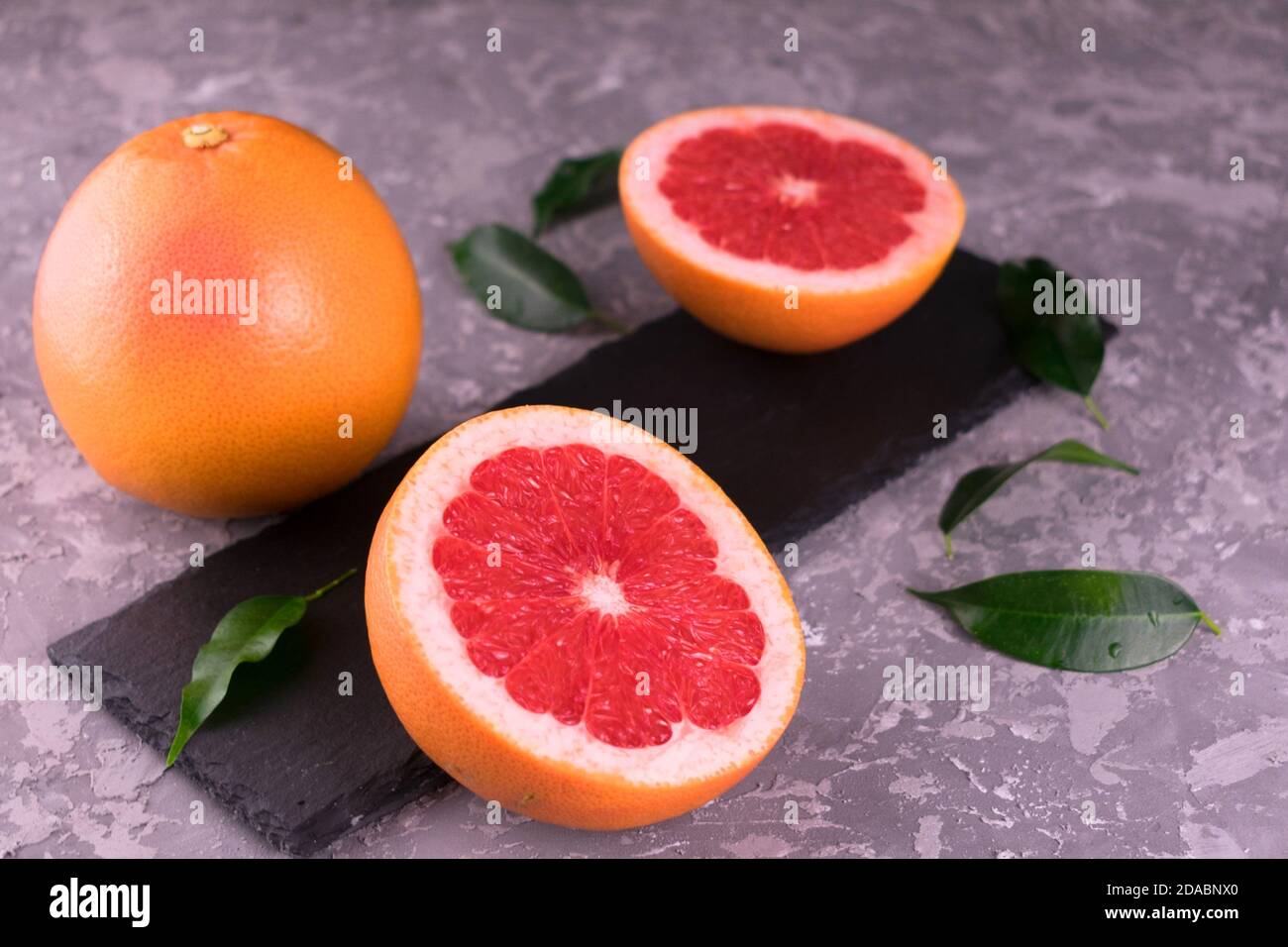 Grapefruit and grapefruit wedges on a gray background. Close-up. Stock Photo