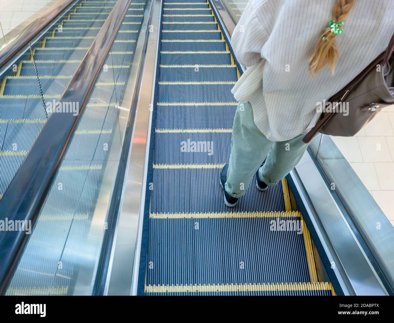 Escalator going down with a girl standing on it in jeans and a shirt