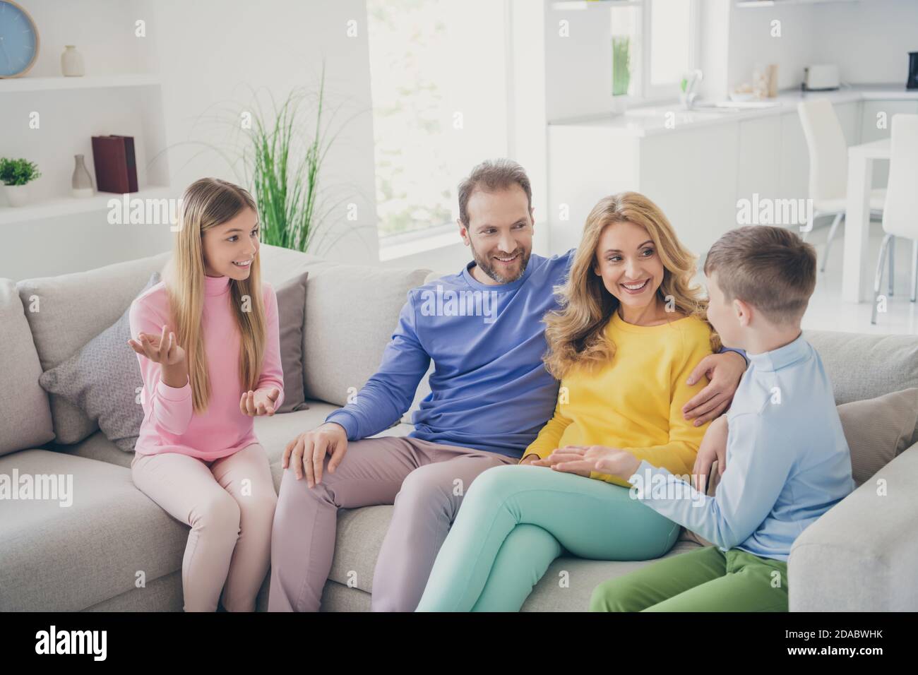 Photo of positive cheerful two kids boy girl sit couch tell mom dad news in house indoors Stock Photo