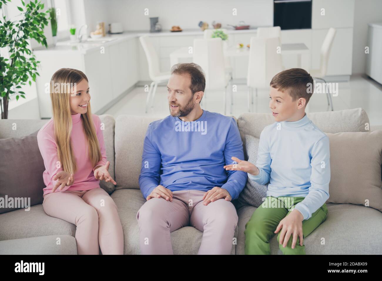 Photo of positive father and two children boy girl talking on weekend sit divan in house living room Stock Photo