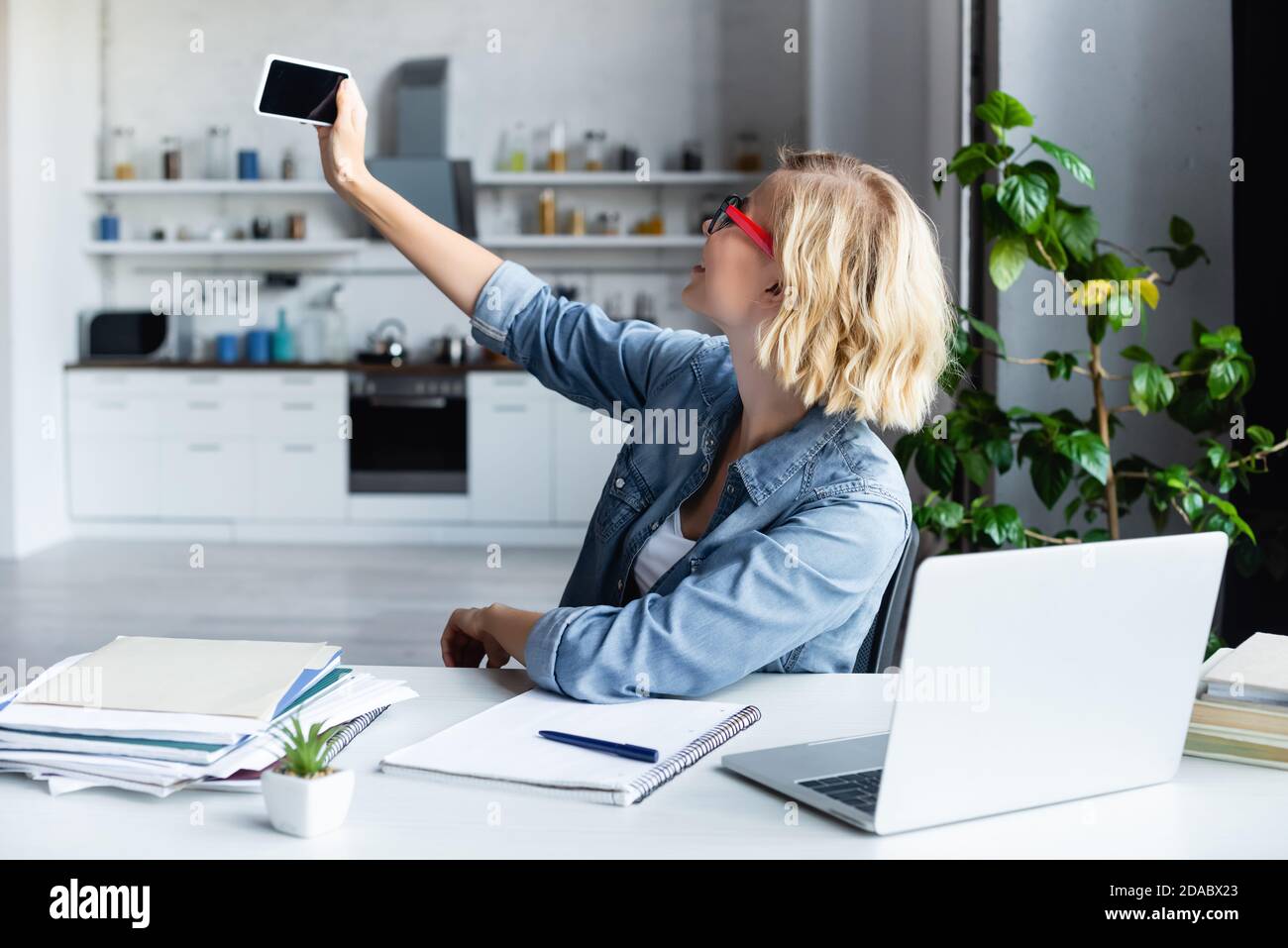 young blonde woman taking selfie while working from home Stock Photo ...