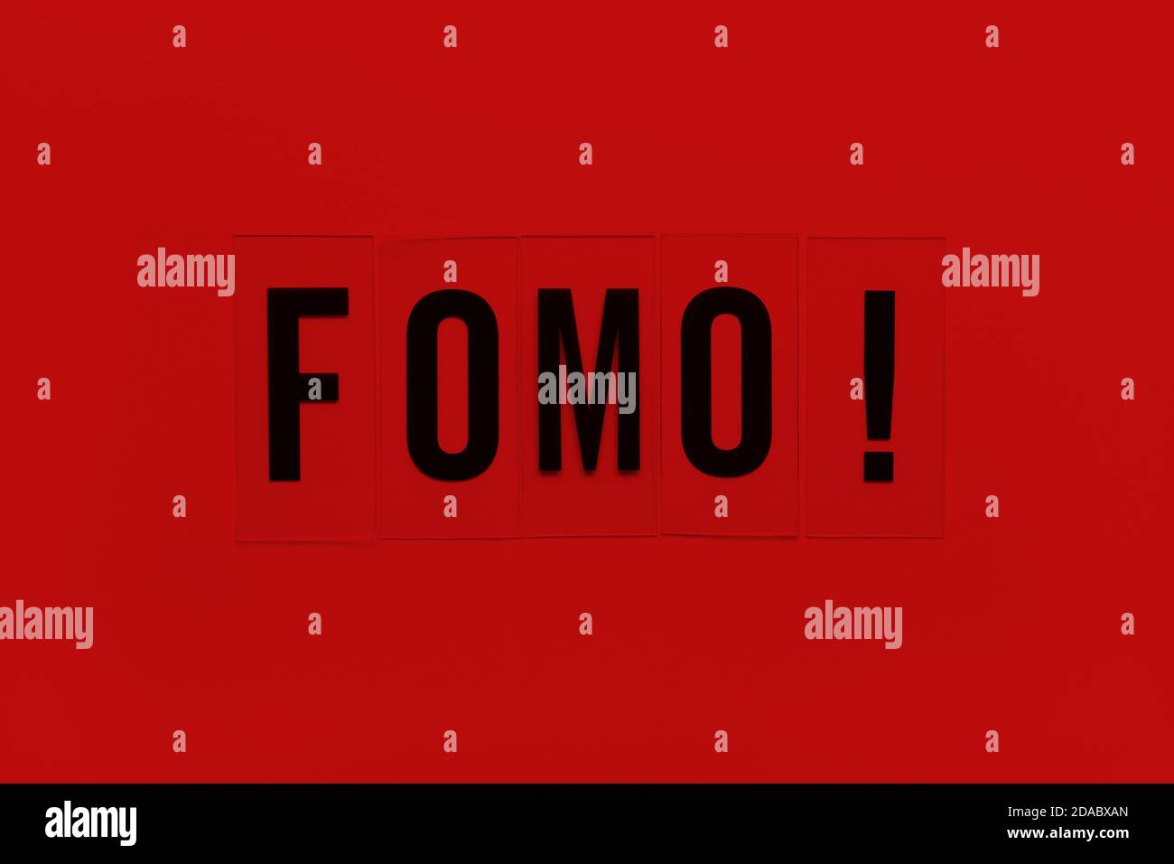 Abbreviation word FOMO on transparent plastic on red background. It means Fear Of Missing Out, non-stop internet surfing. Concept social communication Stock Photo