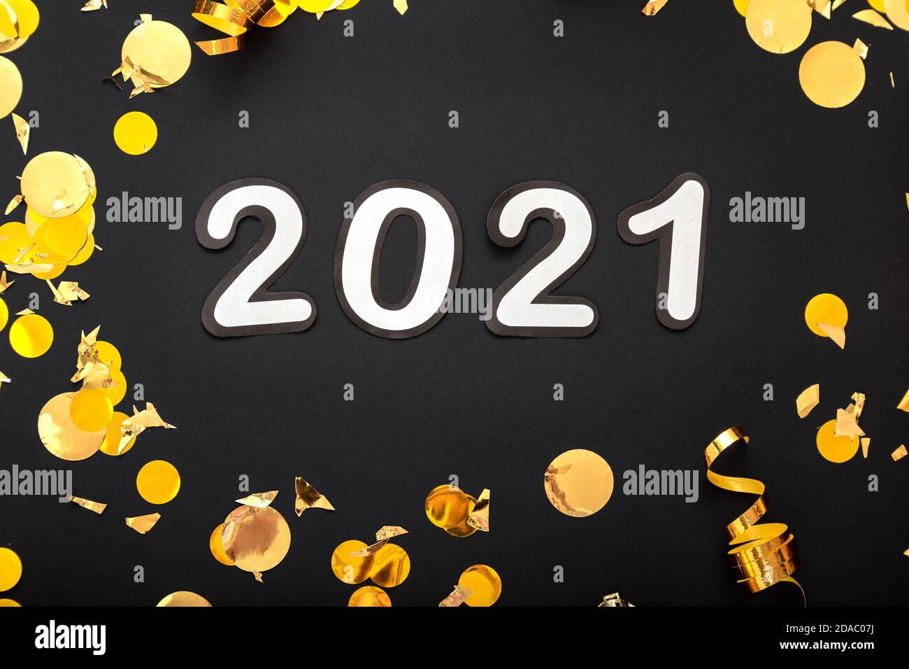 2021 white numbers text lettering in golden confetti, Christmas festive decor frame on black background. Happy New year event composition. Close up Stock Photo