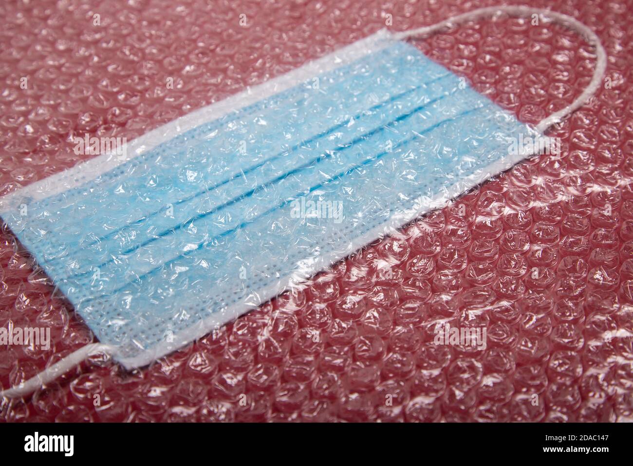 blue mouthguard under a plastic bubble wrap on a red background, perspective view Stock Photo