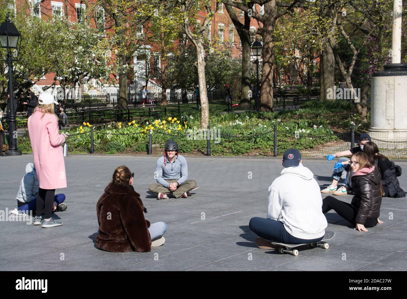 A group of Friends in NYC Park Social Distancing in a Circle Together During Covid-19 Lockdown Stock Photo