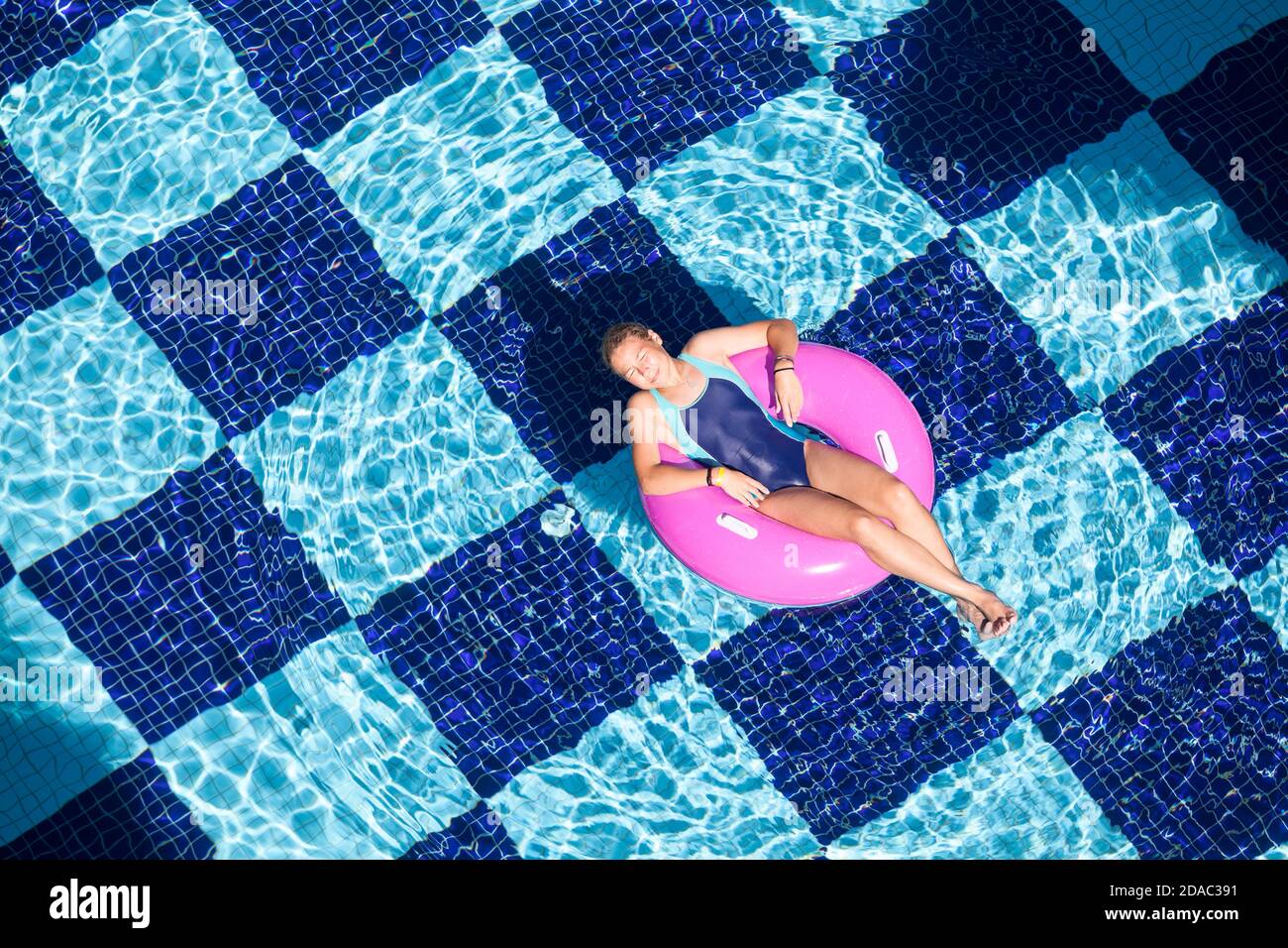Teenage girl swimming in pool with inflatable ring, top view Stock Photo