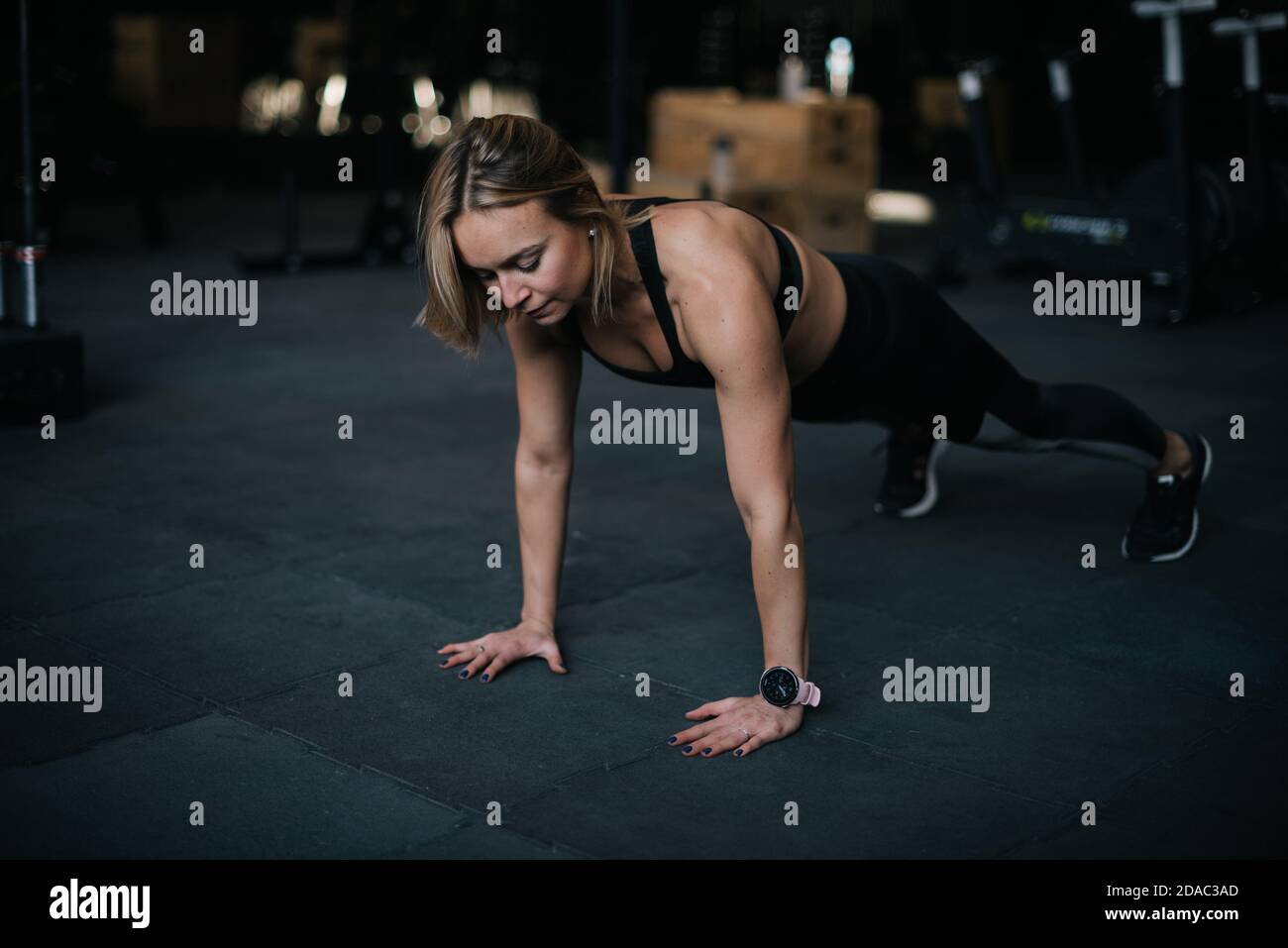 Fitness young woman with perfect athletic body wearing black sportswear doing pushups exercise