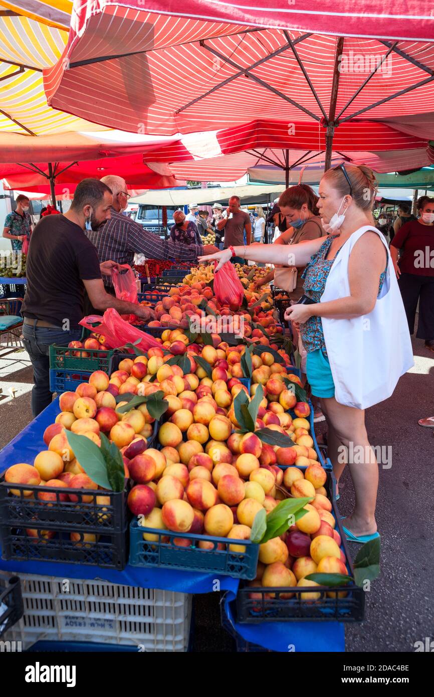Caucasian women buy peaches in local market in city. Seasonal vegetables and fruits are on sale in large bazaar. Alanya, Turkey Stock Photo