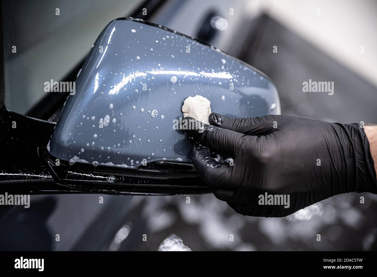 Man car wash worker cleaning car varnish with car clay. Stock Photo