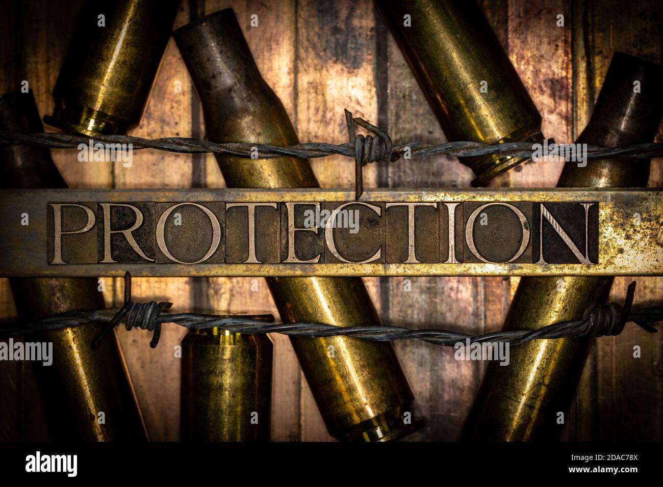 Protection text message over 50 caliber rifle cartridges on vintage textured grunge copper background lined with barbed wire Stock Photo