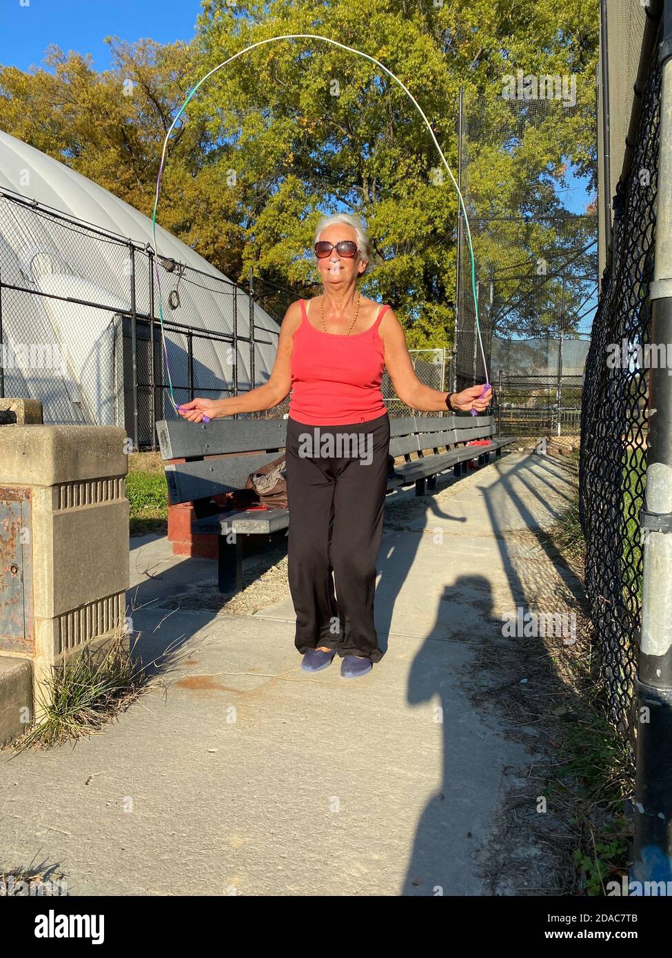 70 year old woman stays in good shape jump roping in the park in Brooklyn, New Yortk. Stock Photo