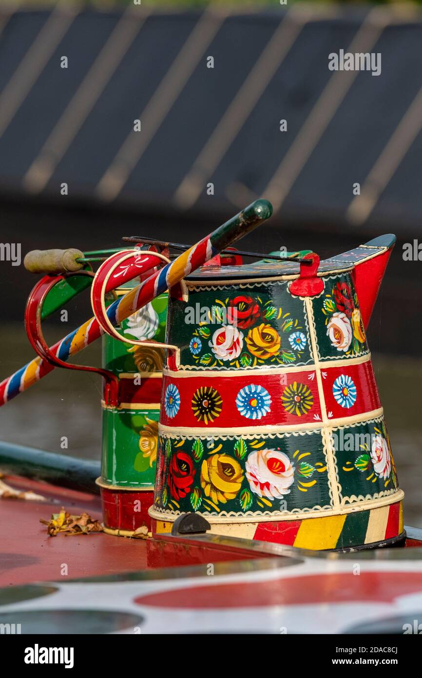 two decorative roses and castles canal wear watering cans or buckets on the top of a traditional narrow boat painted in bright heritage colours. Stock Photo