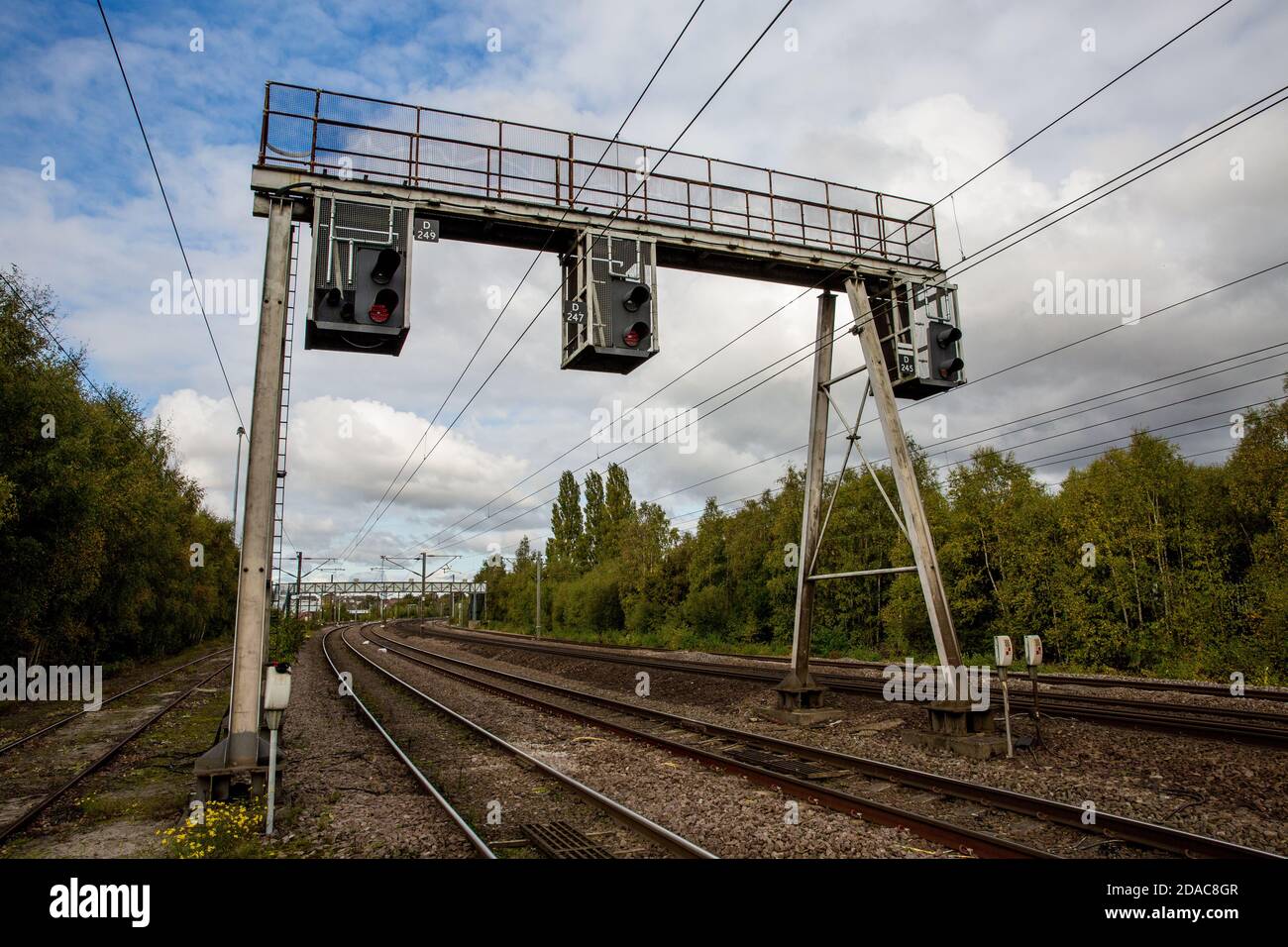 A row of overhead and gantry railway signals that control the movement of trains On UK electrified railway Stock Photo