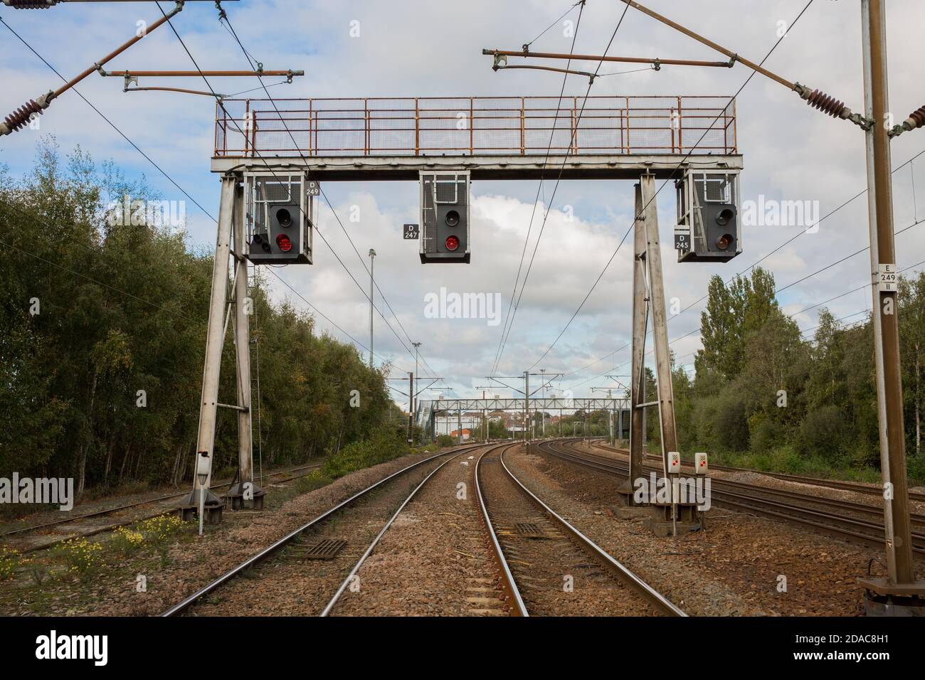 A row of overhead and gantry railway signals that control the movement of trains On UK electrified railway Stock Photo
