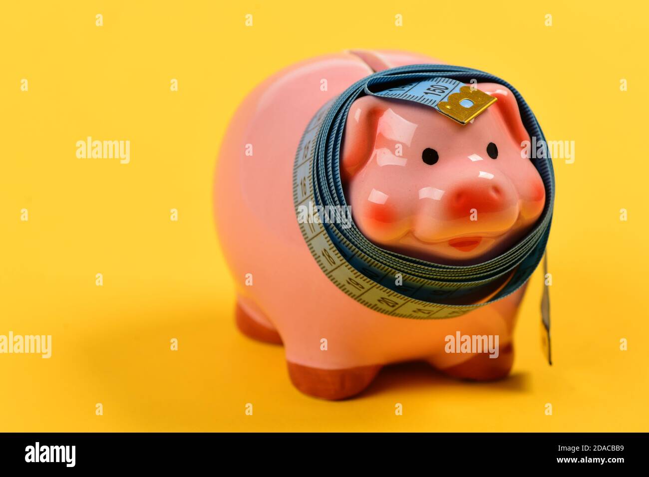 Ceramic toy pig with blue flexible ruler on yellow background