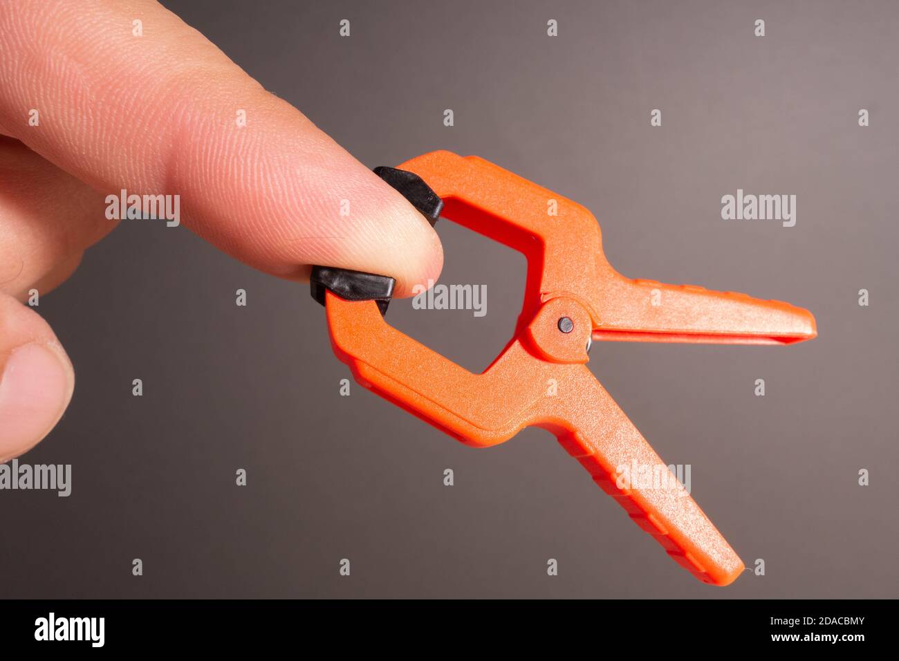 Clothespins, carpentry clamps of orange color lie on a wooden table. A pyramid in the form of a robot made of clamps. Stock Photo