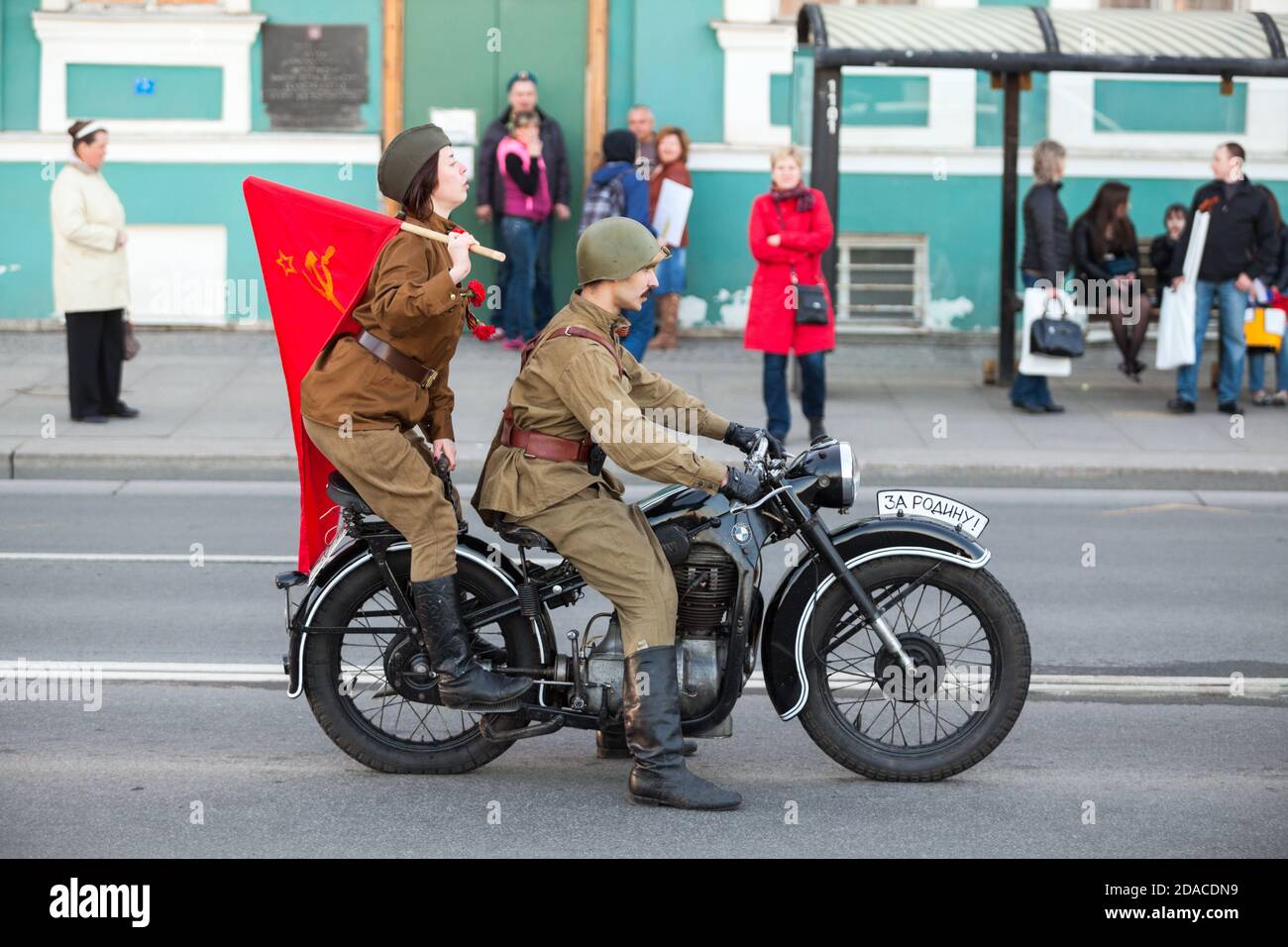 ST. PETERSBURG, RUSSIA-MAY 9, 2015: Soviet loldier with woman dressed military uniform ride on vintage motorcycle in center of city. Celebration of th Stock Photo