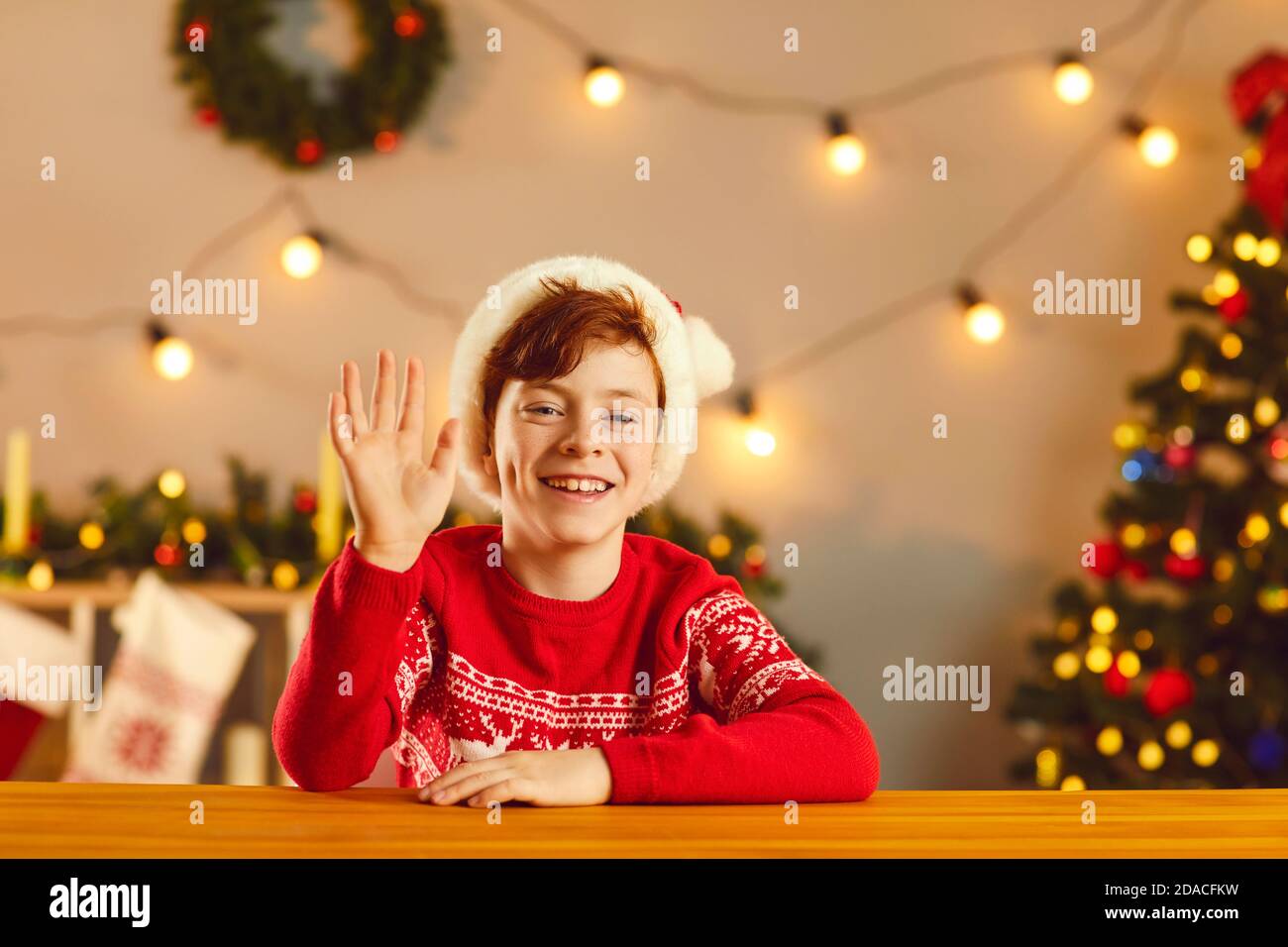 Happy boy smiling and waving hand saying hello during video call or Christmas live stream Stock Photo