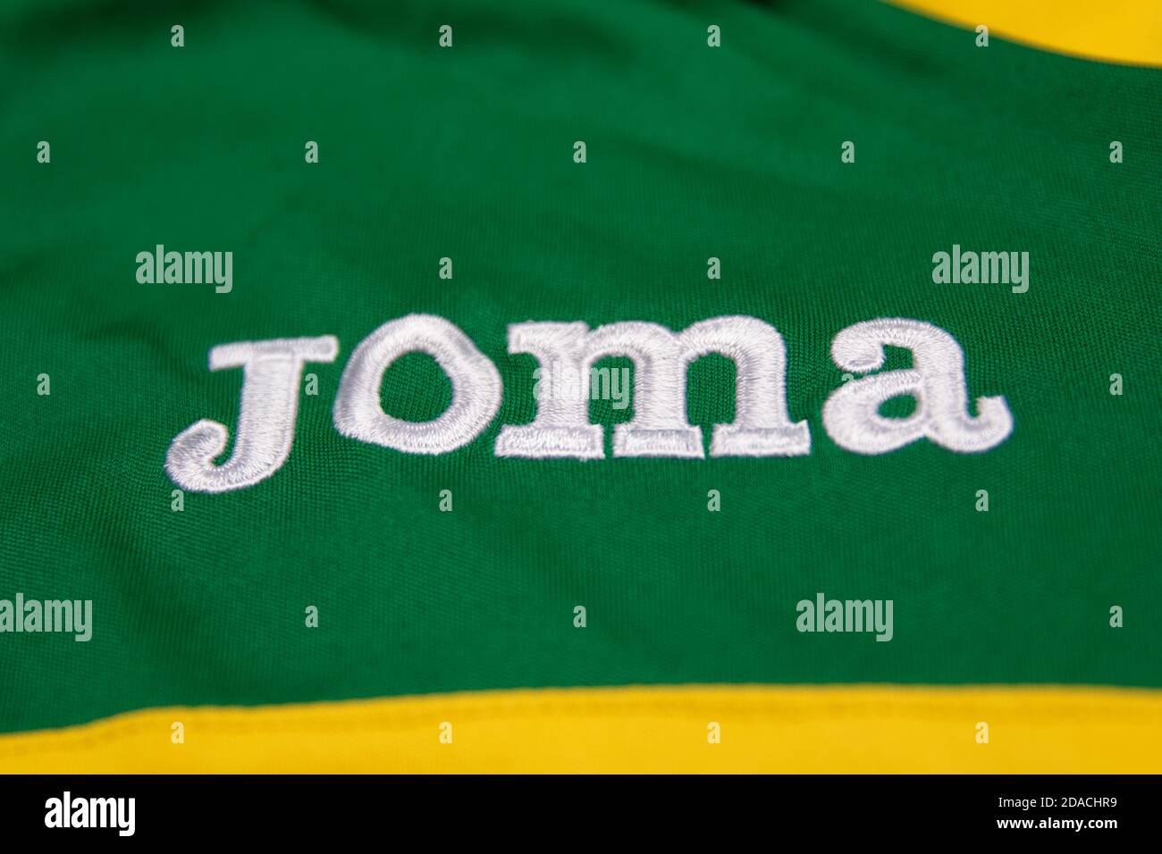 White Joma logo embroidered on a green and yellow sports shirt Stock Photo  - Alamy