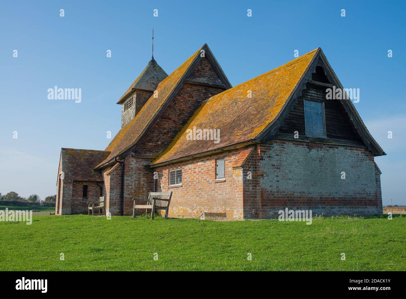 St. Thomas Becket church on a bright sunny afternoon, is an English 13th century church which sits isolated on marshland at Fairfield, Kent, England. Stock Photo