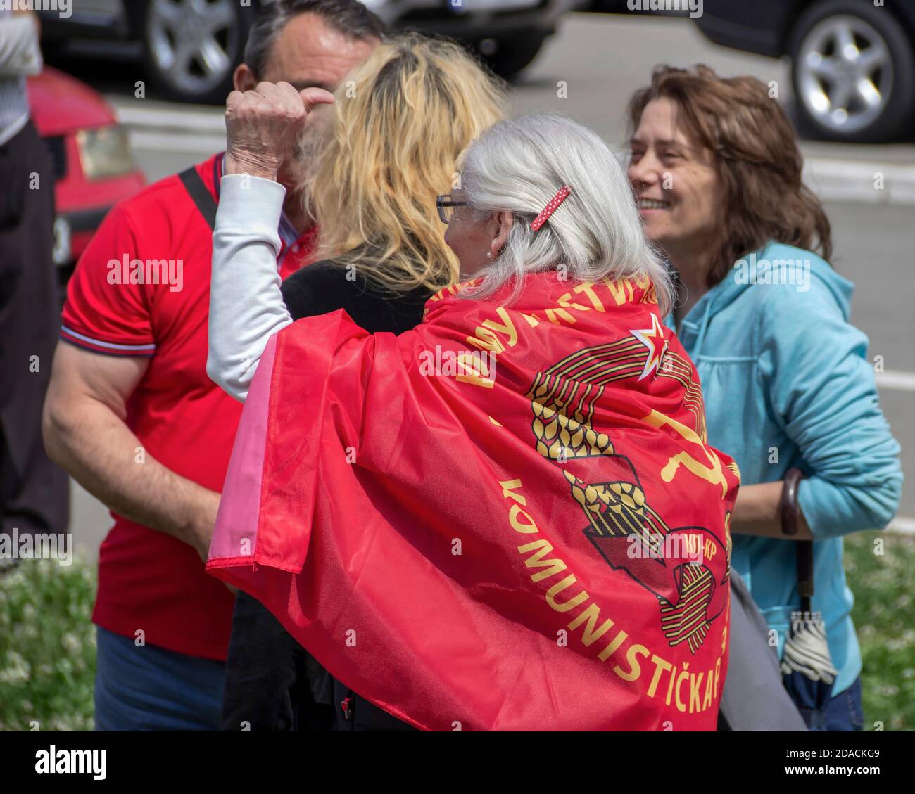 Belgrade, Serbia, May 4, 2017: An elderly lady with a clenched fist wearing the flag of the Communist Party over back during the Yugoslav president Stock Photo