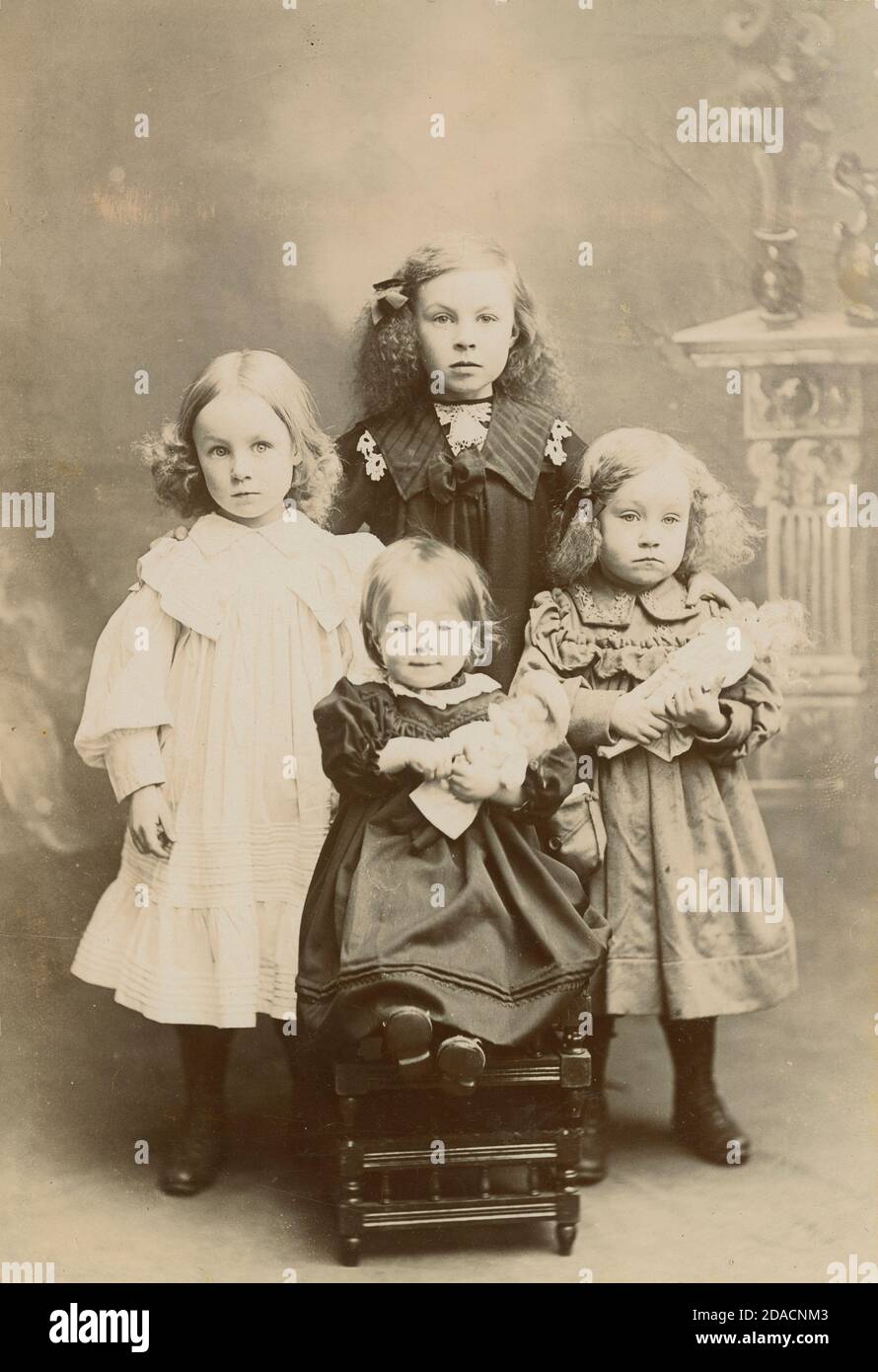 Antique c1880 photograph, four Scottish sisters holding dolls. SOURCE: ORIGINAL CABINET CARD Stock Photo