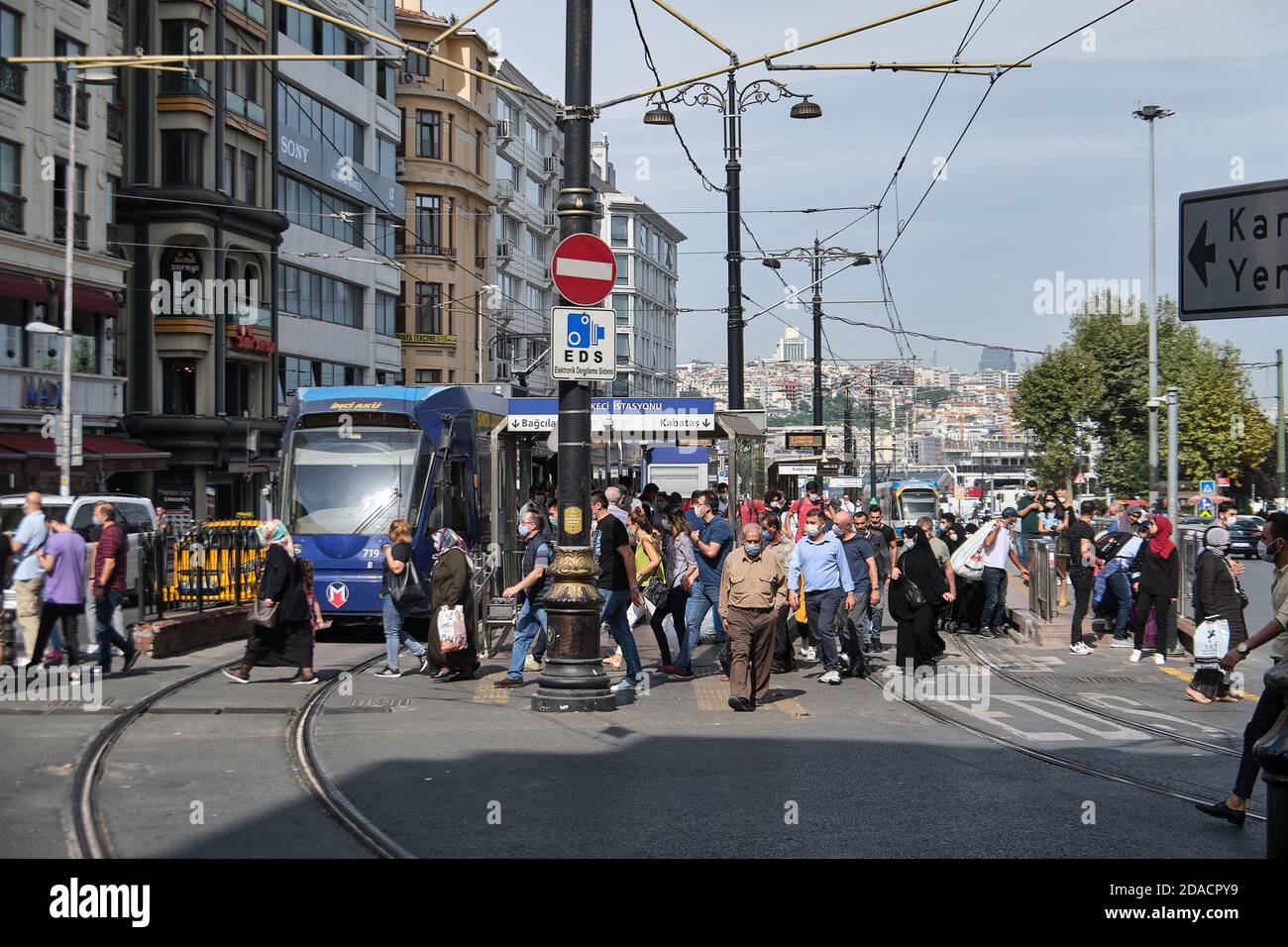 Local people in face masks crossing in front of tram at Sirkeci Istasyonu tram stop, Istanbul, Turkey Stock Photo