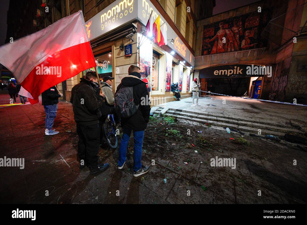 People stand in front of a vandalised Empik book store in central Warsaw,  Poland on November 11, 2020. Despite the intention of Independence Day  march organizers to hold a parade solely by