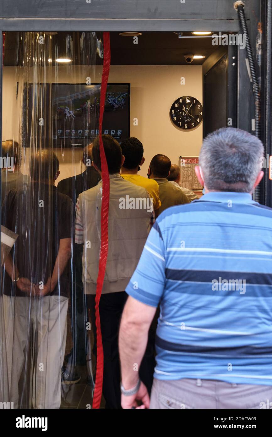 View of local Turkish men watching horse racing inside and outside a betting shop in the back streets of Balat, Istanbul, Turkey Stock Photo