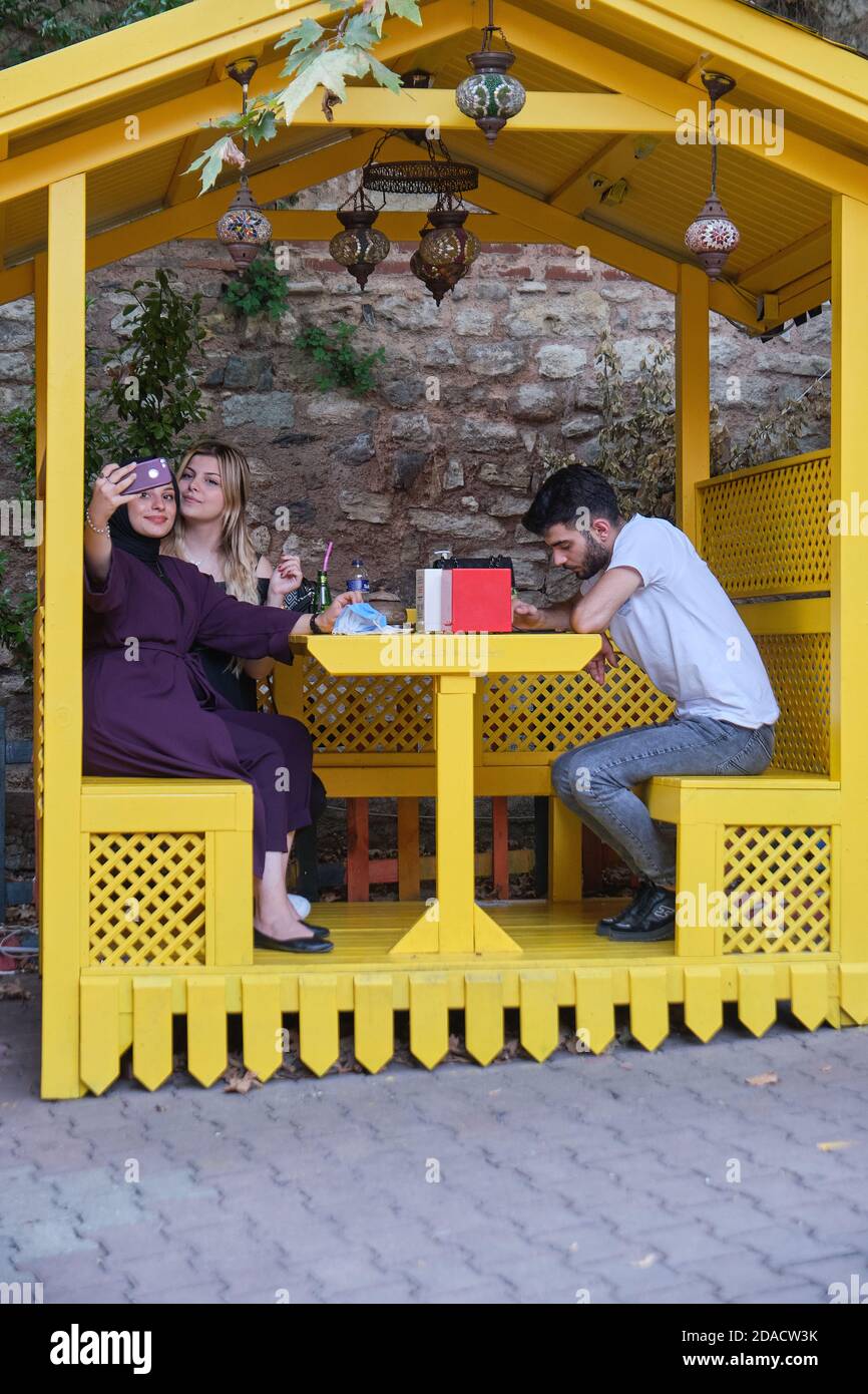Turkish girlfriends taking a selfie photo in a bright yellow eating booth of Antik Cafe in the trendy area of Balat, Istanbul, Turkey Stock Photo